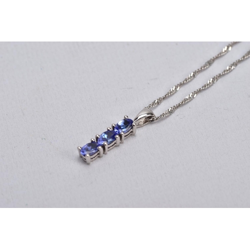 35 - A 9CT WHITE GOLD, TANZANITE PENDANT NECKLACE, the pendant designed with a row of three claw set, ova... 