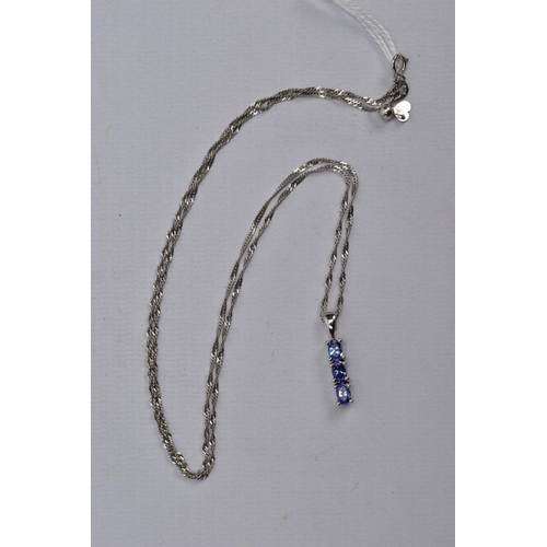 35 - A 9CT WHITE GOLD, TANZANITE PENDANT NECKLACE, the pendant designed with a row of three claw set, ova... 