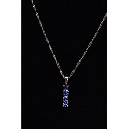 35 - A 9CT WHITE GOLD, TANZANITE PENDANT NECKLACE, the pendant designed with a row of three claw set, ova... 