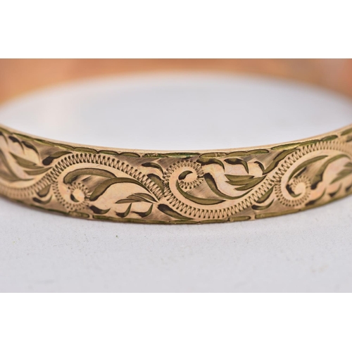 66 - TWO ROLLED GOLD HINGED BANGLES, one with an engraved floral design, the other with a textured design... 