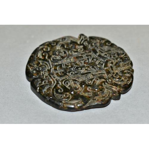 310 - A CHINESE CARVED AND PIERCED CIRCULAR HARDSTONE TABLET, with serpents and scrolls, diameter 6.7cm x ... 