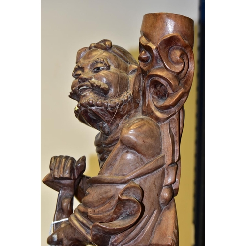 323 - A 20TH CENTURY CHINESE CARVED HARDWOOD FIGURE OF A JOVIAL MAN, holding a staff in both hands, a styl... 