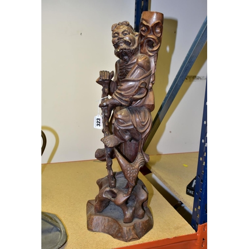 323 - A 20TH CENTURY CHINESE CARVED HARDWOOD FIGURE OF A JOVIAL MAN, holding a staff in both hands, a styl... 