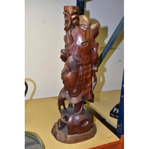 323 - A 20TH CENTURY CHINESE CARVED HARDWOOD FIGURE OF A JOVIAL MAN, holding a staff in both hands, a styl... 