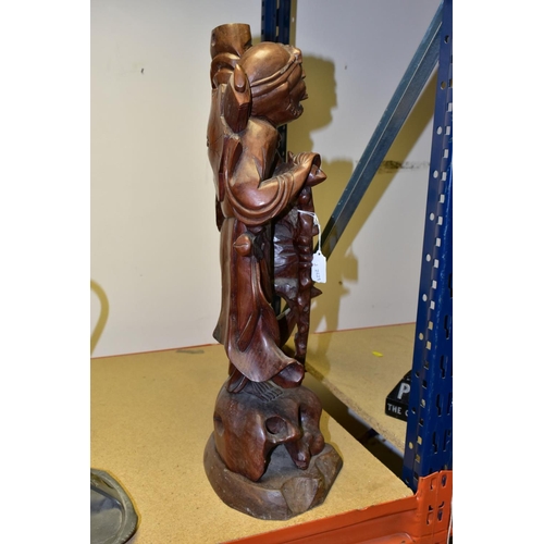 323 - A 20TH CENTURY CHINESE CARVED HARDWOOD FIGURE OF A JOVIAL MAN, holding a staff in both hands, a styl... 