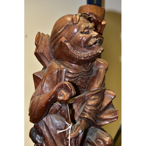 323 - A 20TH CENTURY CHINESE CARVED HARDWOOD FIGURE OF A JOVIAL MAN, holding a staff in both hands, a styl... 