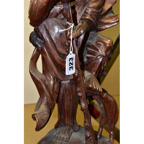 323 - A 20TH CENTURY CHINESE CARVED HARDWOOD FIGURE OF A JOVIAL MAN, holding a staff in both hands, a styl... 