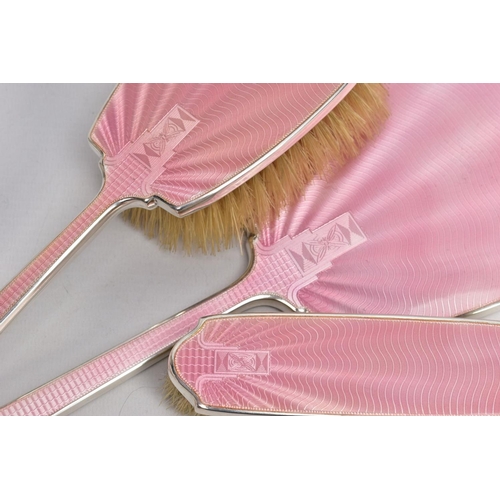 89 - A 1930'S SILVER VANITY SET, comprising of a mirror, and two brushes, one with a handle, with pink en... 