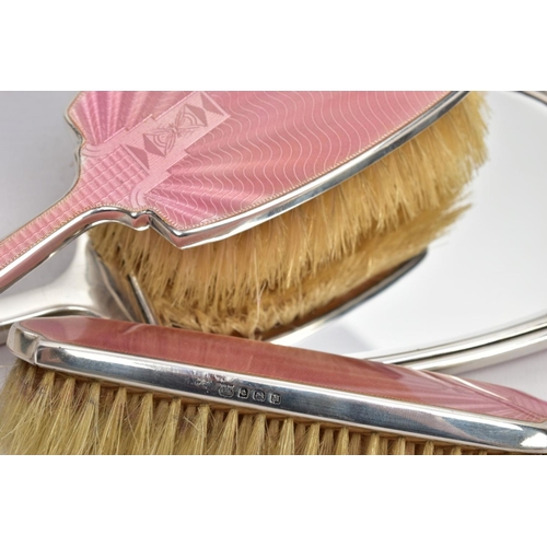 89 - A 1930'S SILVER VANITY SET, comprising of a mirror, and two brushes, one with a handle, with pink en... 
