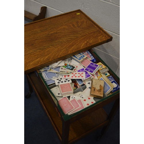 1247 - AN OAK CARD TABLE, the fold over top enclosing a green baize interior, containing a quantity of play... 