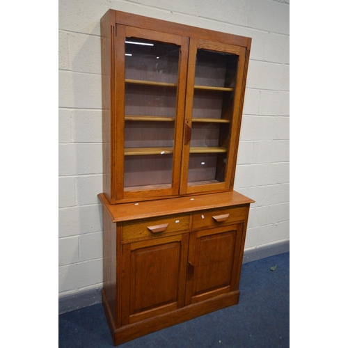 1365 - AN EARLY 20TH CENTURY OAK GLAZED TWO DOOR BOOKCASE, two drawers above two fielded panel doors, width... 