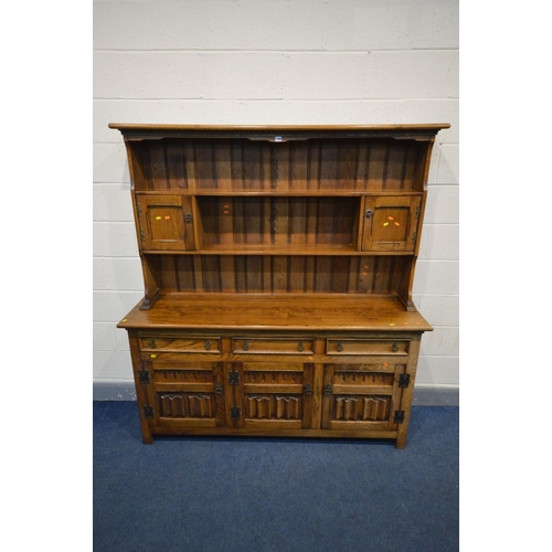 1456 - `A REPRODUCTION OAK DRESSER, the top with a central shelf flanked by two single cupboard doors, the ... 