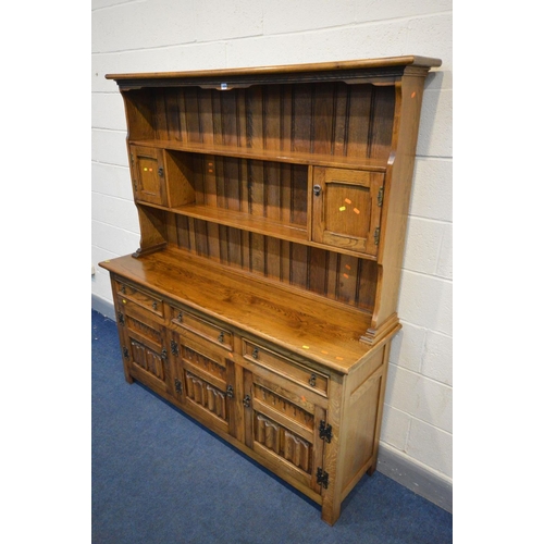 1456 - `A REPRODUCTION OAK DRESSER, the top with a central shelf flanked by two single cupboard doors, the ... 