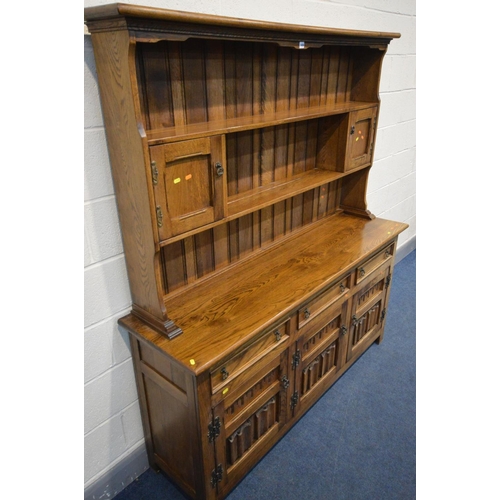 1456 - `A REPRODUCTION OAK DRESSER, the top with a central shelf flanked by two single cupboard doors, the ... 