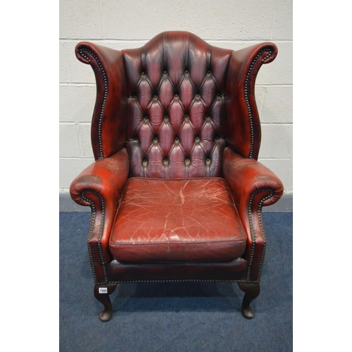 1505 - A BURGUNDY LEATHER BUTTONED WING BACK ARMCHAIR (condition - armrests worn, cracked and one rip, cush... 