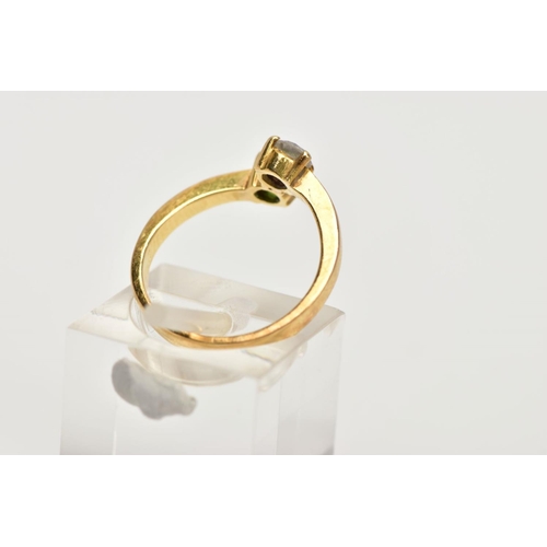 102 - A YELLOW METAL CROSSOVER RING, set with a round brilliant cut diamond, estimated diamond weight 0.20... 