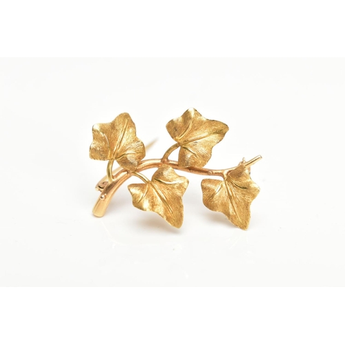 168 - A YELLOW METAL VINE LEAF BROOCH, textured vine leaves on a plain polished stem, fitted with a brooch... 