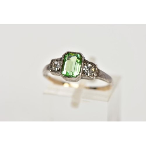 25 - A YELLOW AND WHITE METAL DRESS RING, centring on an emerald cut green paste, flanked with circular c... 