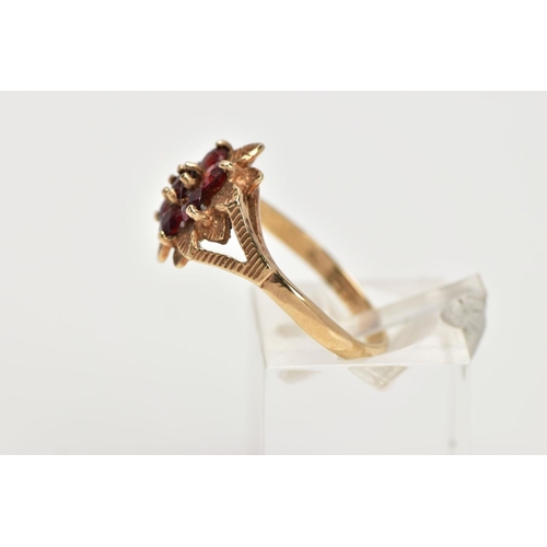 37 - A 9CT GOLD GARNET DRESS RING, of a flower shape, set with seven circular cut garnets, textured leaf ... 