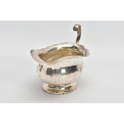 53 - A GEORGE V SILVER SAUCE BOAT, plain polished body, wavy detailed rim, scroll and leaf detailed handl... 