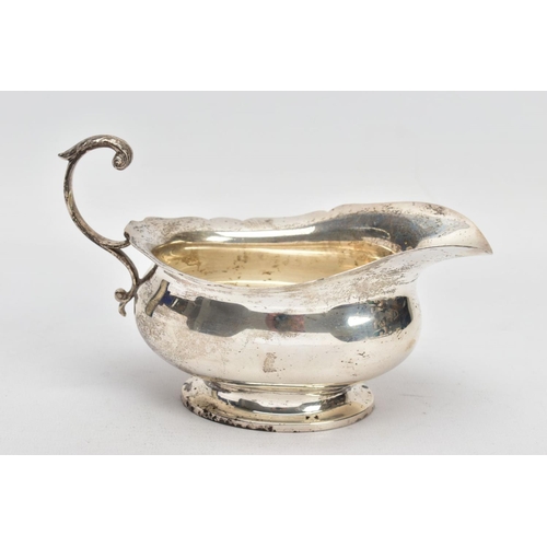 53 - A GEORGE V SILVER SAUCE BOAT, plain polished body, wavy detailed rim, scroll and leaf detailed handl... 