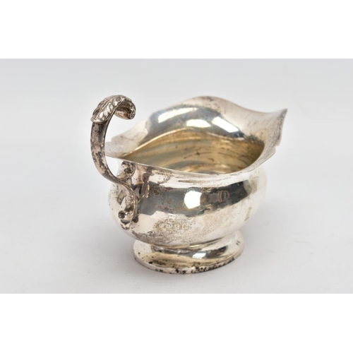 53 - A GEORGE V SILVER SAUCE BOAT, plain polished body, wavy detailed rim, scroll and leaf detailed handl... 