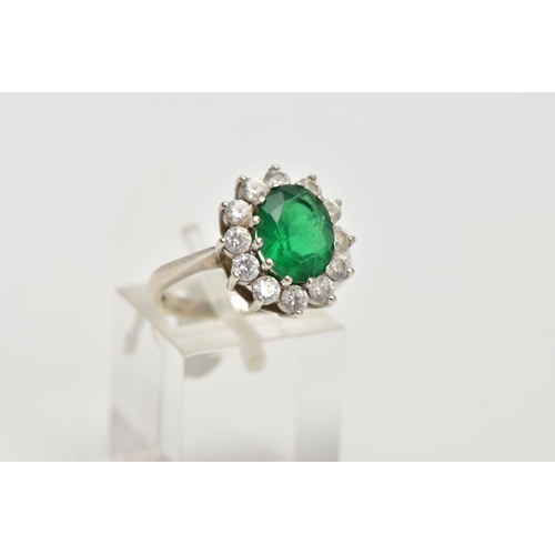 59 - A 9CT WHITE GOLD CLUSTER RING, centring on an oval cut green stone assessed as paste, within a surro... 