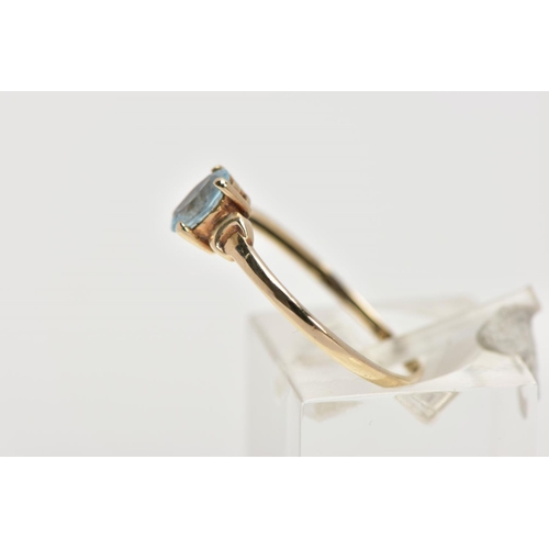 8 - A YELLOW METAL TOPAZ RING, designed with a claw set, oval cut blue topaz, detailed shoulders, plain ... 