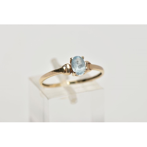 8 - A YELLOW METAL TOPAZ RING, designed with a claw set, oval cut blue topaz, detailed shoulders, plain ... 