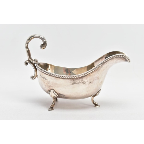 81 - AN EARLY 20TH CENTURY SILVER GRAVY BOAT, with gadrooned top edge, scrolling handle and three feet, s... 