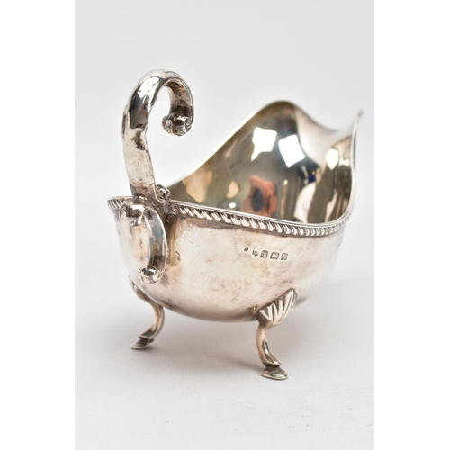 81 - AN EARLY 20TH CENTURY SILVER GRAVY BOAT, with gadrooned top edge, scrolling handle and three feet, s... 