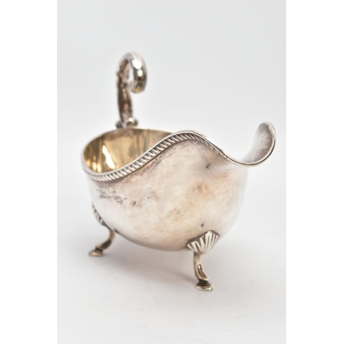 81 - AN EARLY 20TH CENTURY SILVER GRAVY BOAT, with gadrooned top edge, scrolling handle and three feet, s... 