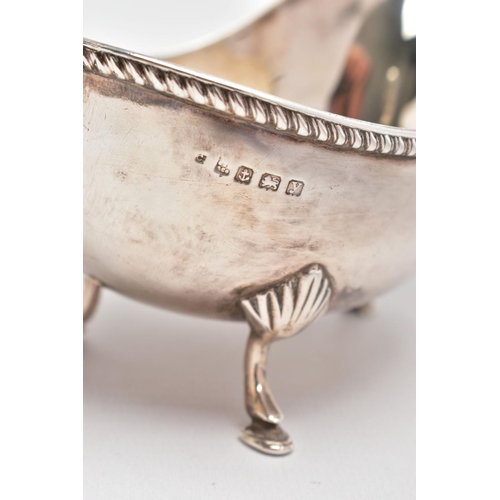 81 - AN EARLY 20TH CENTURY SILVER GRAVY BOAT, with gadrooned top edge, scrolling handle and three feet, s... 