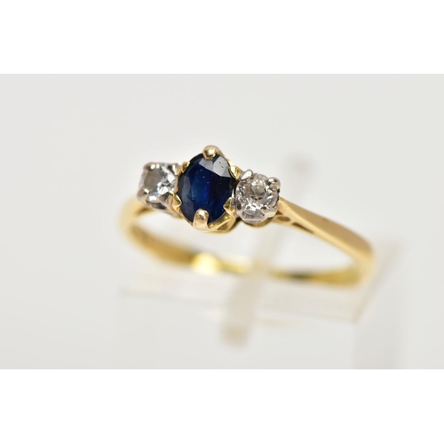 99 - AN 18CT GOLD SAPPHIRE AND DIAMOND THREE STONE RING, centring on a claw set, oval cut blue sapphire, ... 