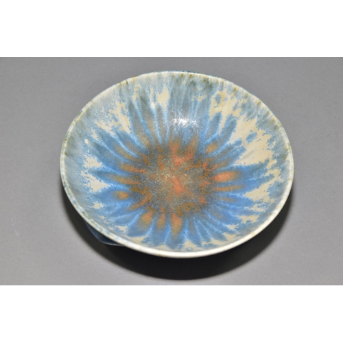 197 - RUSKIN POTTERY, a shallow bowl raised on three feet, blue and orange crystalline glaze over white gl... 