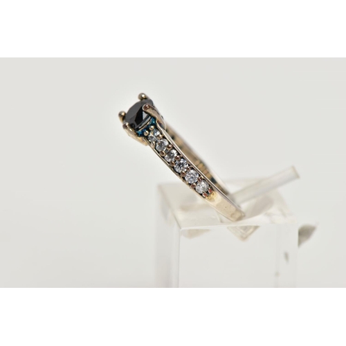 10 - A WHITE METAL CUBIC ZIRCONIA SET DRESS RING, designed with a central, circular cut black stone, flan... 