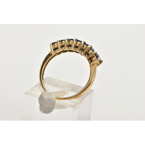 12 - A 9CT GOLD SAPPHIRE DRESS RING, of a half hoop design, set with a row seven claw set, oval cut, blue... 