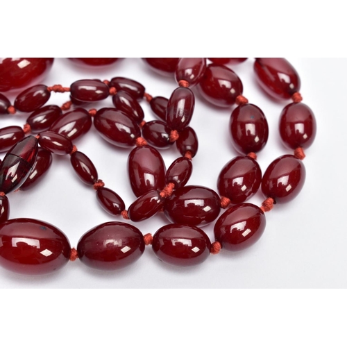 31 - A CHERRY AMBER STYLE BAKELITE BEAD NECKLACE, graduated oval beads individually knotted on a red cord... 