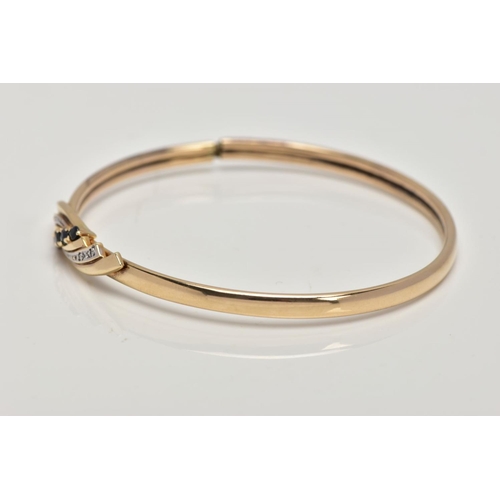 188 - A 9CT GOLD SAPPHIRE AND DIAMOND HINGED BANGLE, the centre designed with a curved cross over section,... 