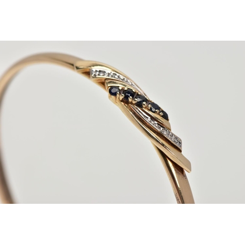 188 - A 9CT GOLD SAPPHIRE AND DIAMOND HINGED BANGLE, the centre designed with a curved cross over section,... 