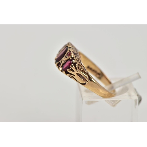 268 - A 9CT GOLD THREE STONE GARNET RING, designed with a row of three graduated oval cut garnets, intersp... 