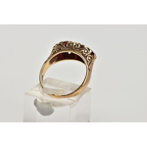 268 - A 9CT GOLD THREE STONE GARNET RING, designed with a row of three graduated oval cut garnets, intersp... 