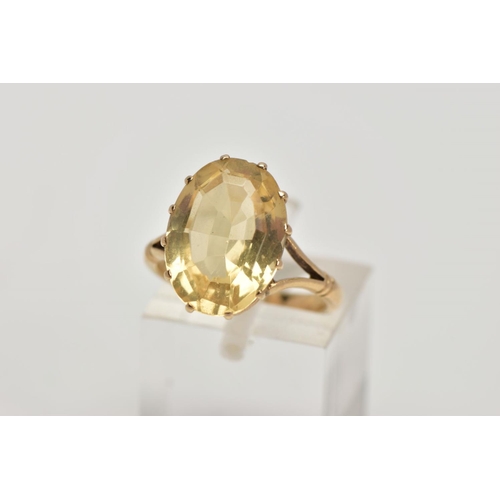 272 - A YELLOW METAL CITRINE DRESS RING, designed with a claw set oval cut citrine, openwork gallery, bifu... 