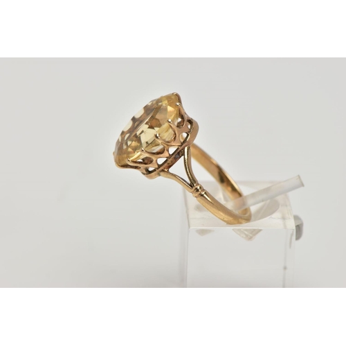 272 - A YELLOW METAL CITRINE DRESS RING, designed with a claw set oval cut citrine, openwork gallery, bifu... 