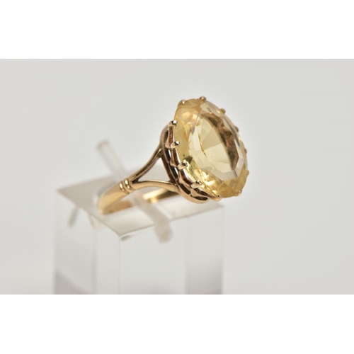 272 - A YELLOW METAL CITRINE DRESS RING, designed with a claw set oval cut citrine, openwork gallery, bifu... 