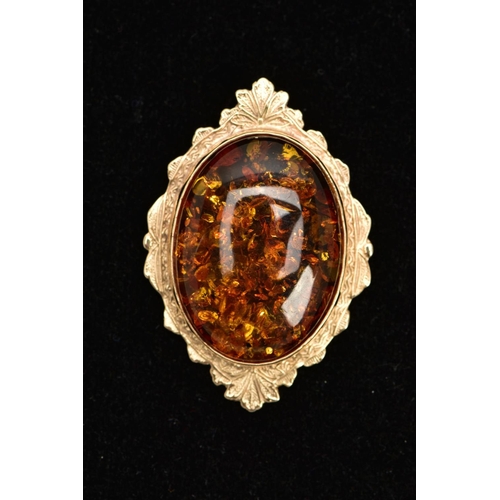 111 - A 9CT GOLD AMBER PENDANT, large oval amber cabochon, collet mounted within a decorative foliate surr... 