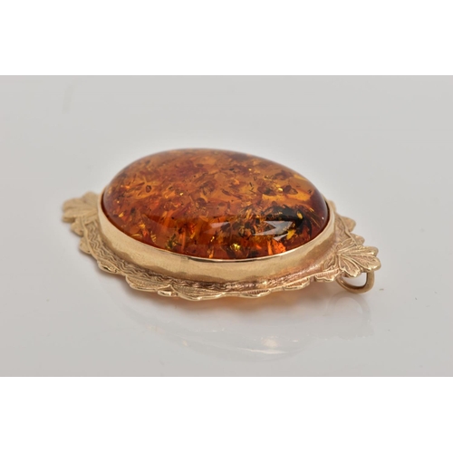 111 - A 9CT GOLD AMBER PENDANT, large oval amber cabochon, collet mounted within a decorative foliate surr... 