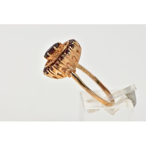 42 - A YELLOW METAL GARNET CLUSTER RING, of an oval form, centring on a six claw set, oval cut garnet, wi... 