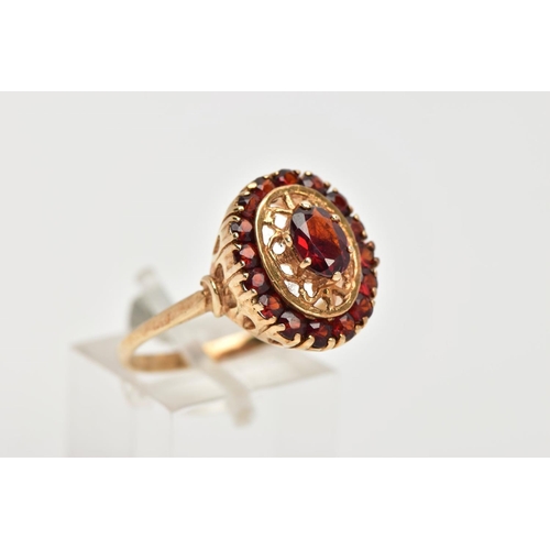 42 - A YELLOW METAL GARNET CLUSTER RING, of an oval form, centring on a six claw set, oval cut garnet, wi... 