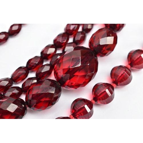 58 - TWO SETS OF FACETED CHERRY AMBER PLASTIC BEAD NECKLACES, the first designed with circular faceted be... 